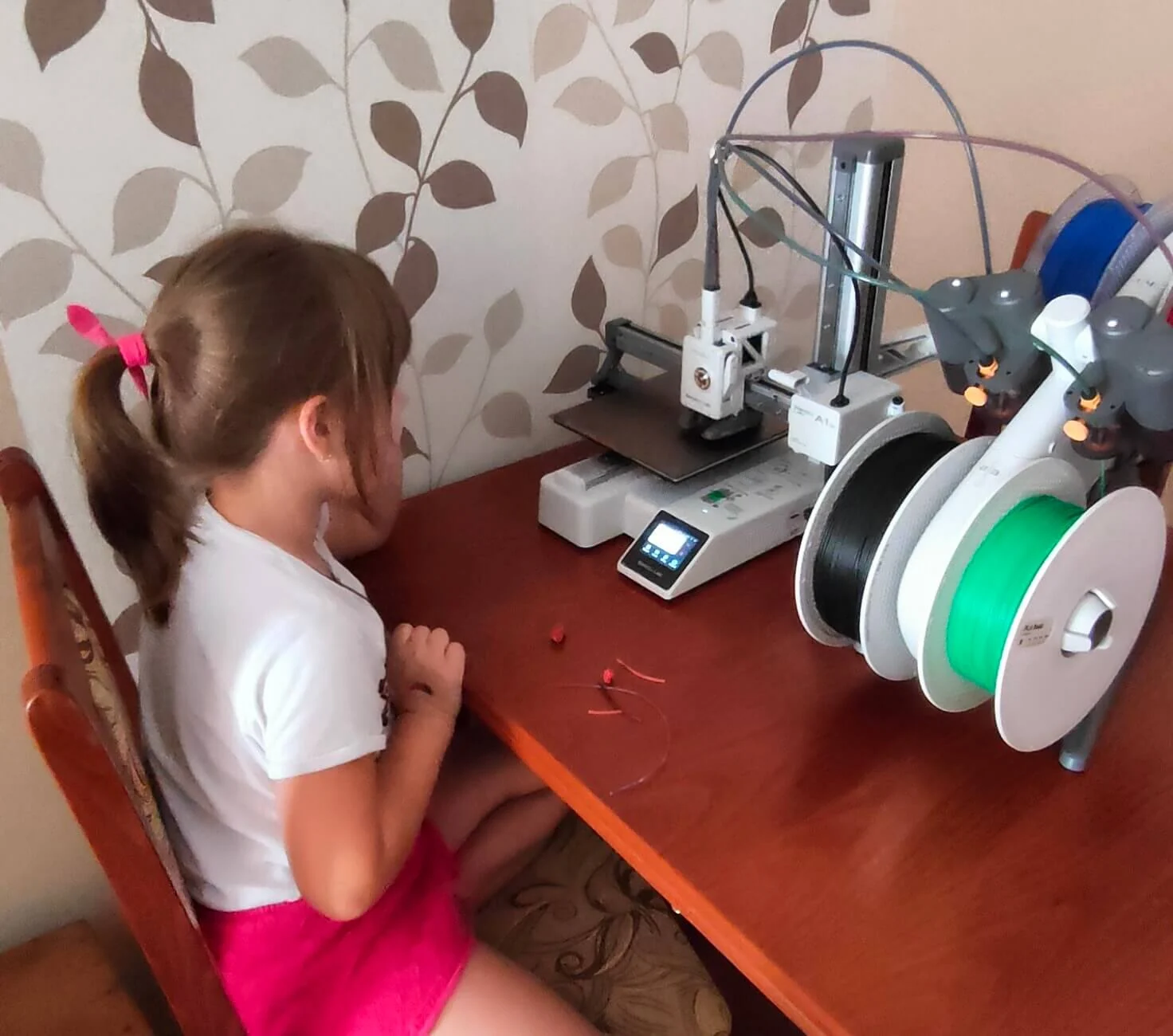 Dítě sleduje tiskárnu Bambu Lab A1 Mini při práci